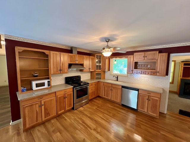 kitchen featuring decorative backsplash, light wood-type flooring, stainless steel appliances, ceiling fan, and sink