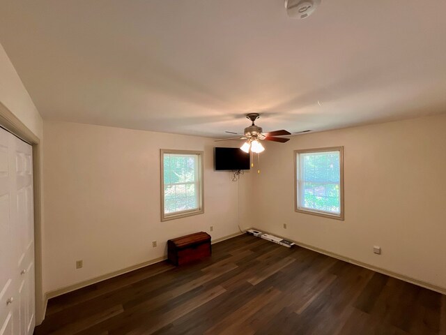 unfurnished bedroom with ceiling fan and dark wood-type flooring