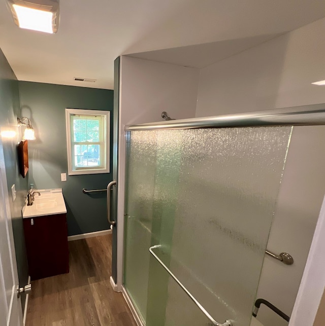 bathroom with hardwood / wood-style flooring, vanity, and walk in shower