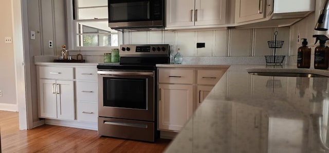 10117 Pine Ave, Nassawadox, VA 23413 - kitchen featuring baseboards, stainless steel appliances, white cabinets, and light wood-style floors