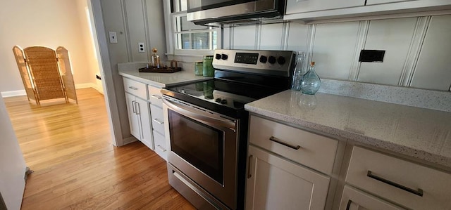 10117 Pine Ave, Nassawadox, VA 23413 - kitchen with light wood finished floors, electric range, baseboards, light stone countertops, and white cabinetry