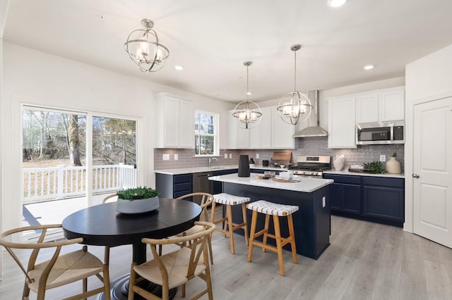 kitchen featuring a center island, white cabinets, stainless steel appliances, and decorative light fixtures