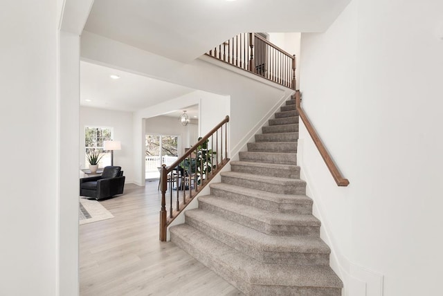 stairway featuring hardwood / wood-style flooring and an inviting chandelier