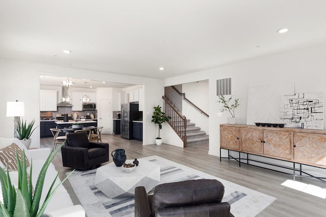 living room featuring light wood-type flooring and a notable chandelier