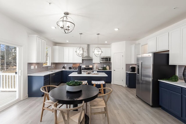 kitchen featuring stainless steel appliances, blue cabinetry, decorative light fixtures, white cabinets, and a kitchen island