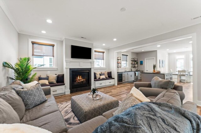 living room featuring dark hardwood / wood-style floors, wine cooler, ornamental molding, and sink