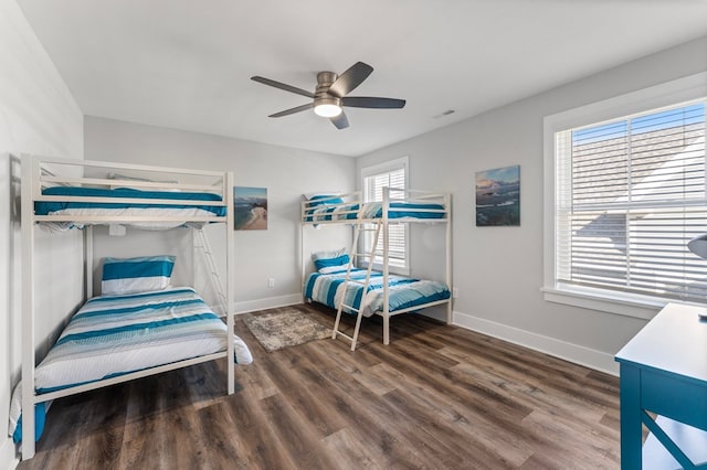 bedroom with ceiling fan, dark wood-type flooring, and multiple windows