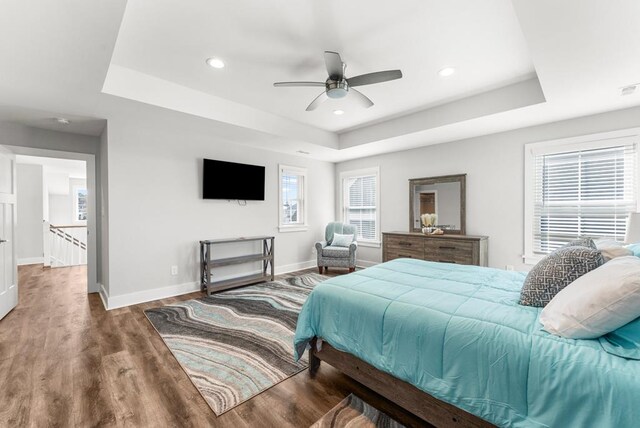 bedroom with ceiling fan, a raised ceiling, and dark wood-type flooring