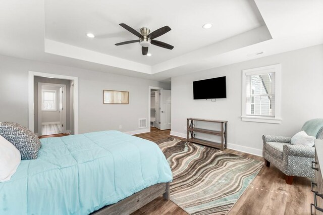 bedroom featuring ceiling fan, dark wood-type flooring, and a tray ceiling