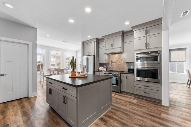 kitchen with decorative backsplash, gray cabinets, dark wood-type flooring, and high quality appliances