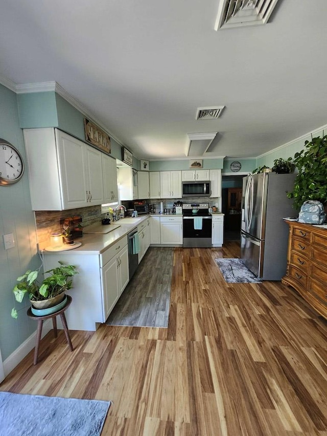 kitchen featuring sink, stainless steel appliances, backsplash, light hardwood / wood-style floors, and white cabinets