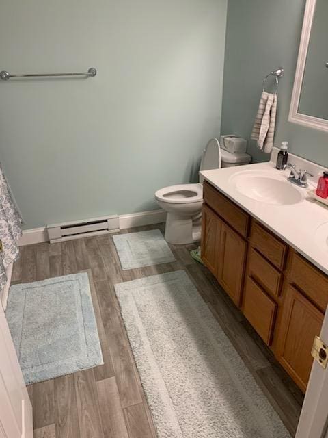 bathroom with vanity, toilet, wood-type flooring, and a baseboard heating unit