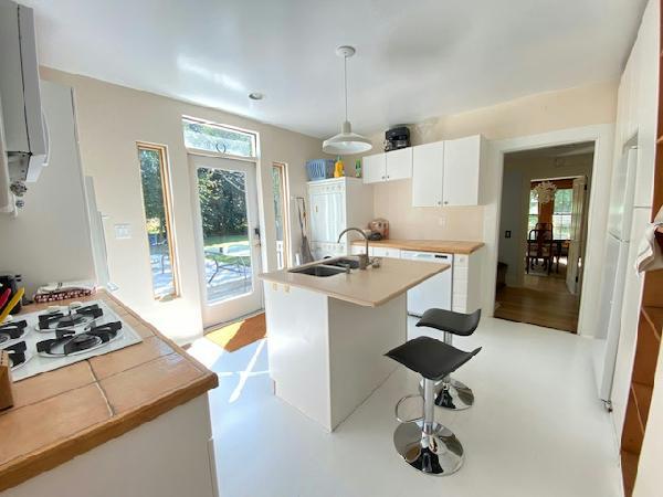 kitchen featuring a kitchen bar, white appliances, sink, white cabinets, and hanging light fixtures