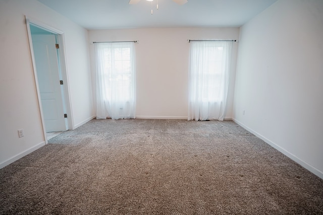 carpeted empty room with a ceiling fan, a wealth of natural light, and baseboards