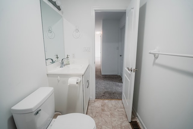 bathroom with toilet, vanity, and baseboards