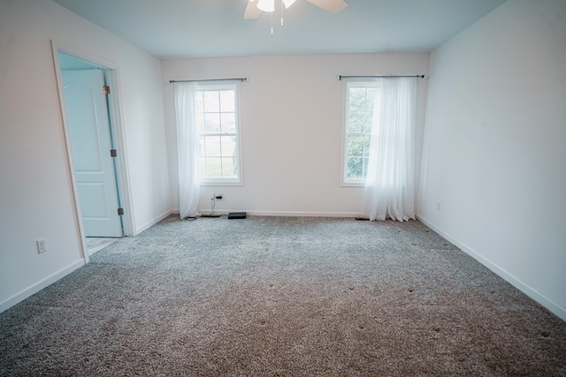 carpeted spare room featuring baseboards and ceiling fan