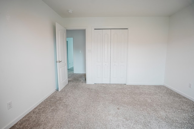 unfurnished bedroom featuring a closet, baseboards, and carpet floors