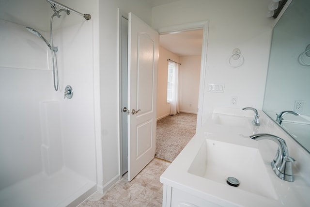 bathroom with a stall shower, double vanity, and a sink