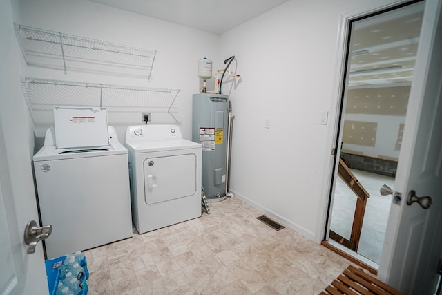 laundry area featuring visible vents, baseboards, water heater, separate washer and dryer, and laundry area