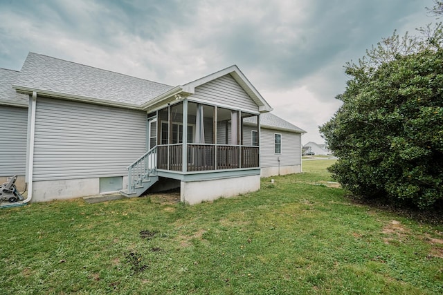 back of property featuring a lawn, a shingled roof, and a sunroom