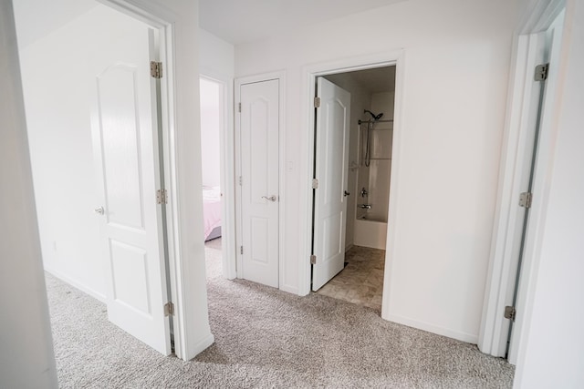 corridor with baseboards and light colored carpet