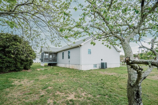 view of property exterior featuring a lawn, central AC, and a sunroom