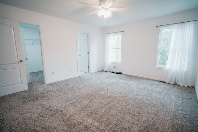 unfurnished bedroom featuring ceiling fan, a closet, baseboards, carpet floors, and a spacious closet