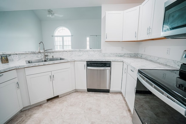 kitchen featuring light stone counters, appliances with stainless steel finishes, a sink, white cabinetry, and a ceiling fan