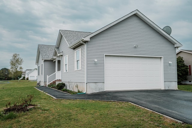view of side of home featuring a garage, driveway, a yard, and roof with shingles