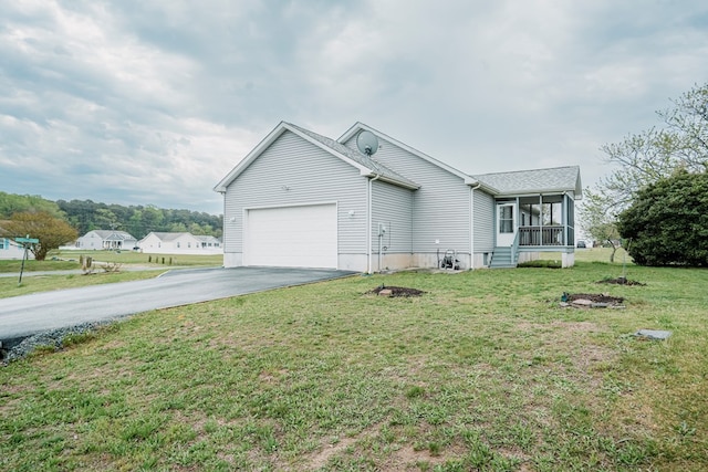single story home with a garage, a front lawn, driveway, and a sunroom