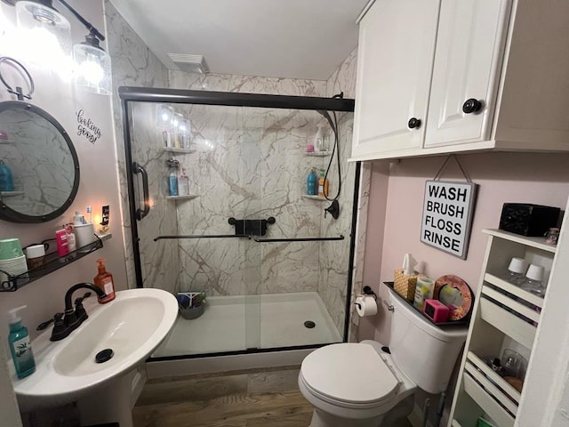 bathroom with hardwood / wood-style floors, toilet, a shower with shower door, and sink