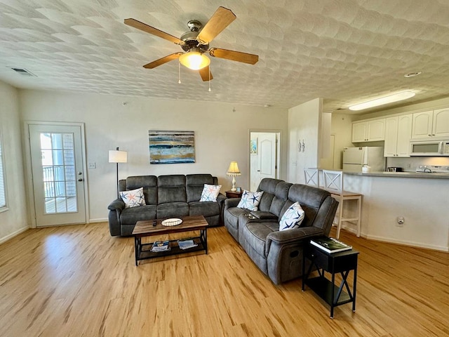 living room with ceiling fan and light hardwood / wood-style flooring