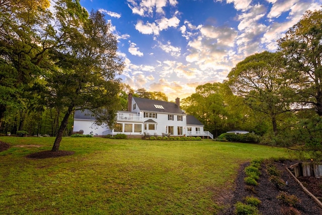 back of property at dusk featuring a yard and a chimney