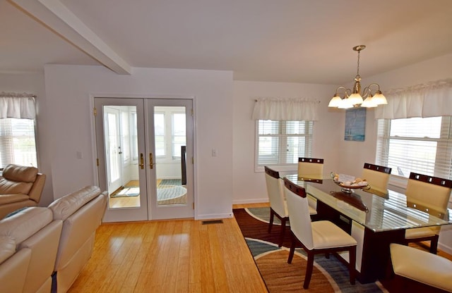 dining area featuring a chandelier, french doors, light wood-type flooring, and beamed ceiling