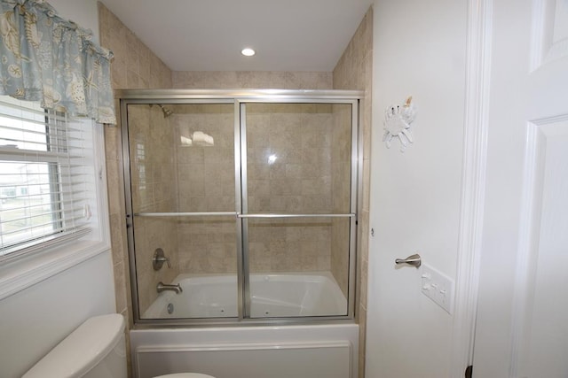 bathroom featuring toilet and bath / shower combo with glass door