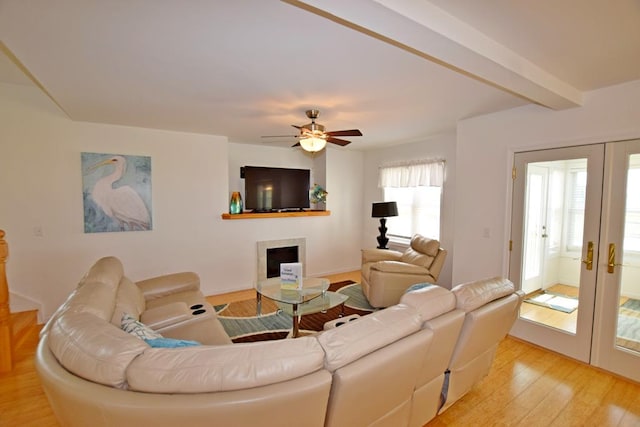 living room with beamed ceiling, ceiling fan, light hardwood / wood-style flooring, and french doors