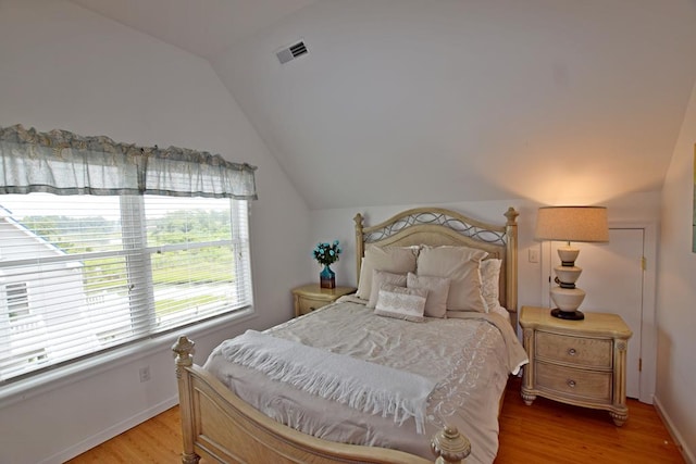 bedroom with light wood-type flooring and vaulted ceiling