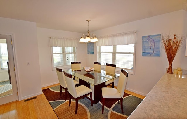 dining space with hardwood / wood-style floors and an inviting chandelier