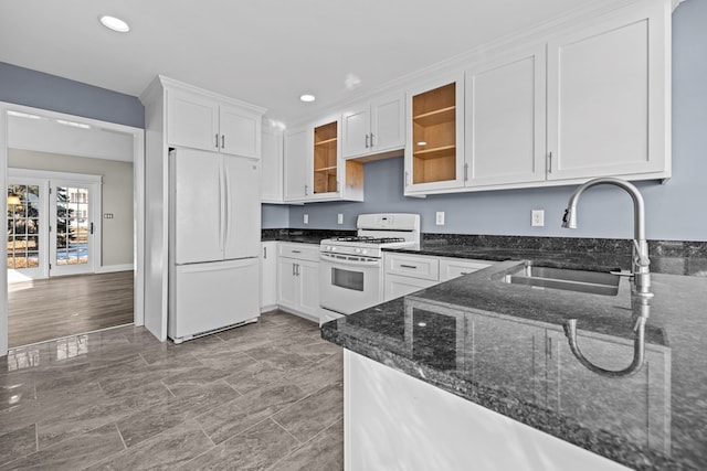 kitchen with white cabinetry, sink, dark stone countertops, and white appliances