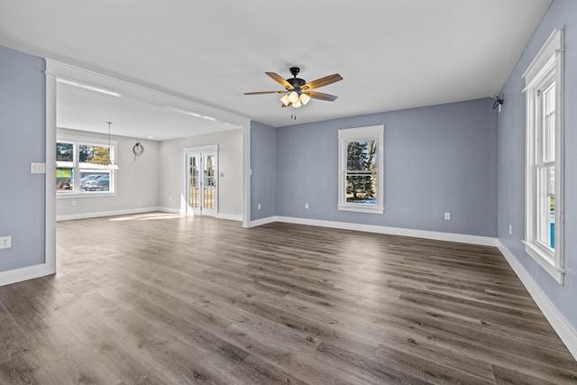 unfurnished living room featuring dark wood-type flooring and ceiling fan