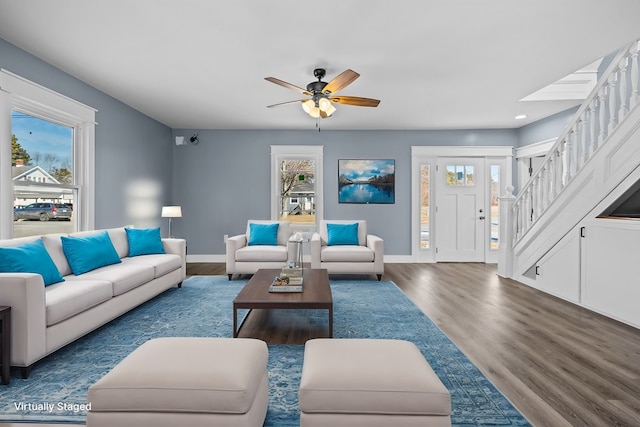 living room featuring dark wood-type flooring, ceiling fan, and plenty of natural light