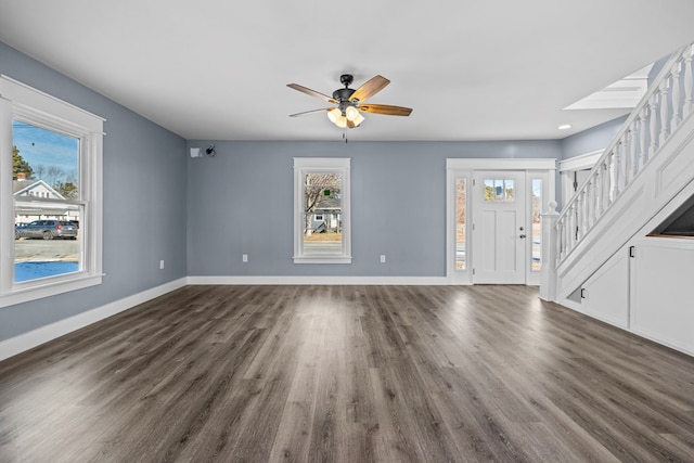 unfurnished living room featuring dark wood-type flooring, ceiling fan, and plenty of natural light