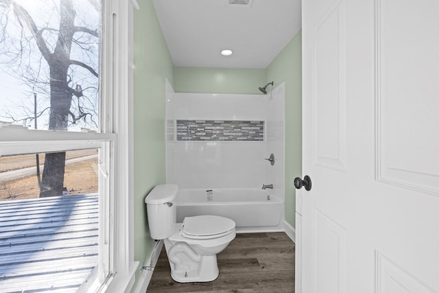 bathroom featuring hardwood / wood-style flooring, shower / tub combination, and toilet