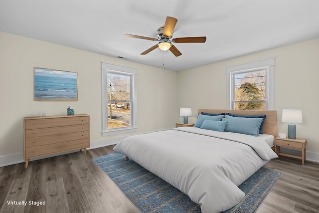 bedroom featuring multiple windows, hardwood / wood-style floors, and ceiling fan