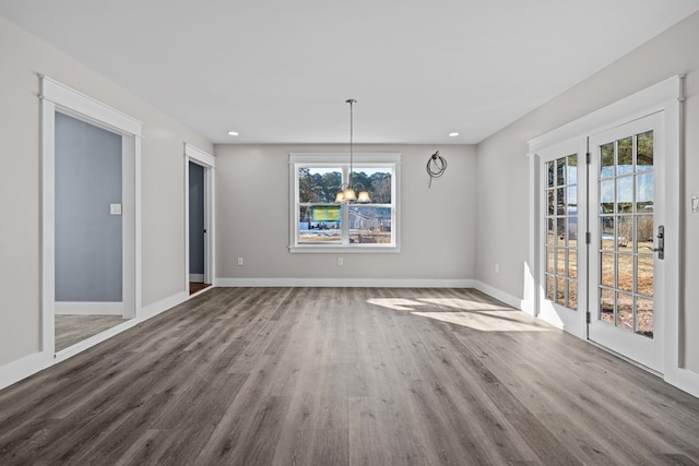 unfurnished dining area featuring wood-type flooring, a wealth of natural light, and a chandelier