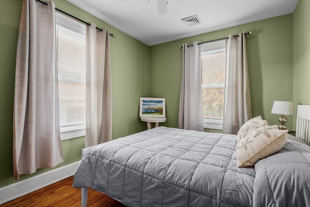 bedroom with multiple windows, wood-type flooring, and ceiling fan