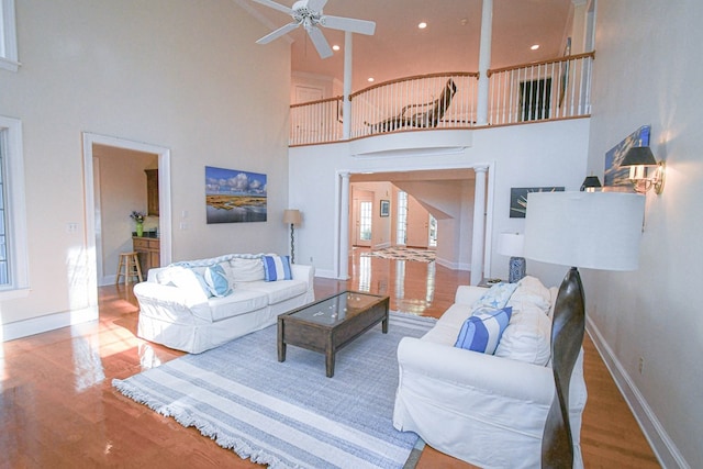 living room featuring a high ceiling, wood-type flooring, and ceiling fan