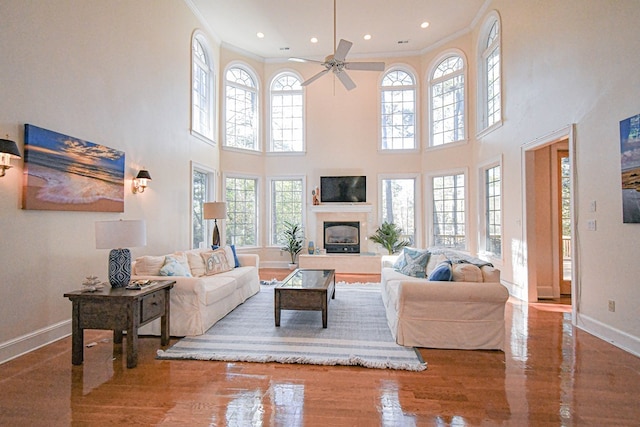 living room featuring hardwood / wood-style floors, a towering ceiling, ornamental molding, and ceiling fan