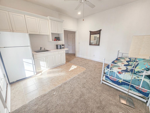 interior space with sink, light carpet, white fridge, ceiling fan, and white cabinets