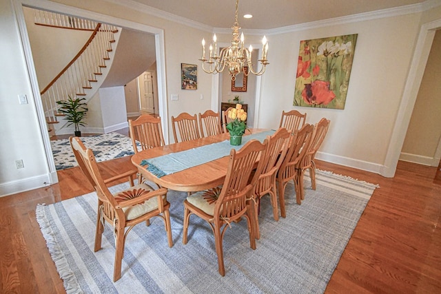 dining space featuring hardwood / wood-style floors, crown molding, and a chandelier